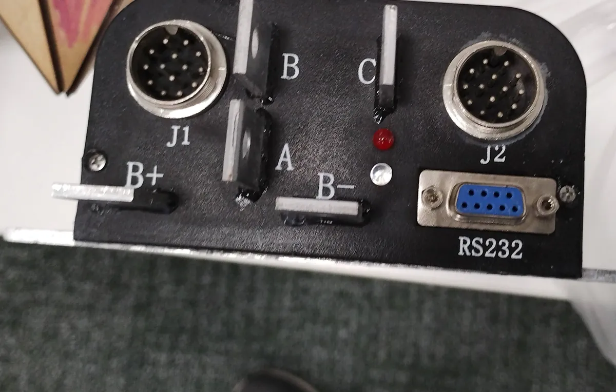 Black control box panel with two round multi-pin connectors, an RS232 port and labelled terminals
