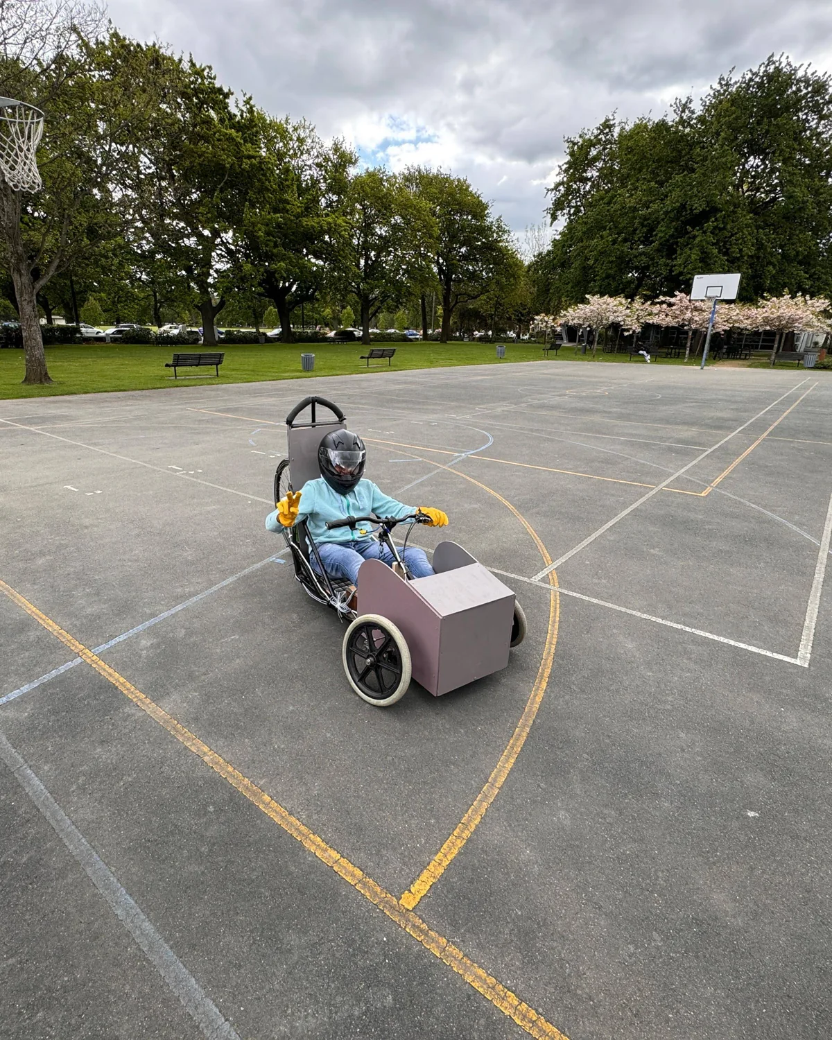 Vishan in a helmet driving the electric kart across a basketball court in Christchurch, 2023