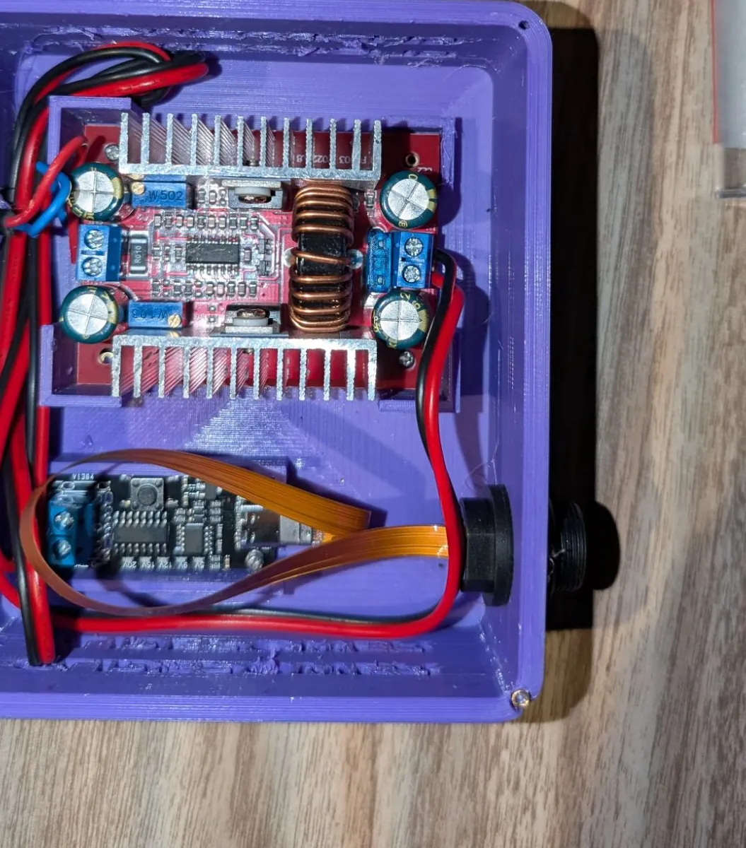 Inside the purple box: the red step-up converter with two heatsinks and a toroid, the USB-C trigger board on a ribbon cable, and the output jack