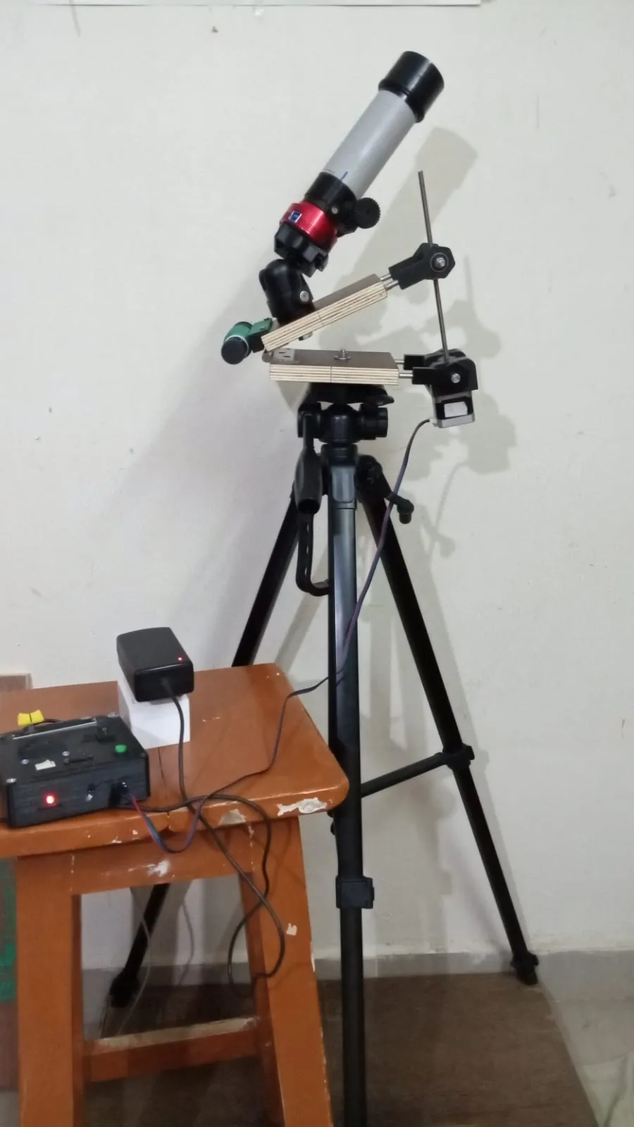The tracker on a tripod carrying a small refractor telescope, with the control box and power supply on a stool beside it